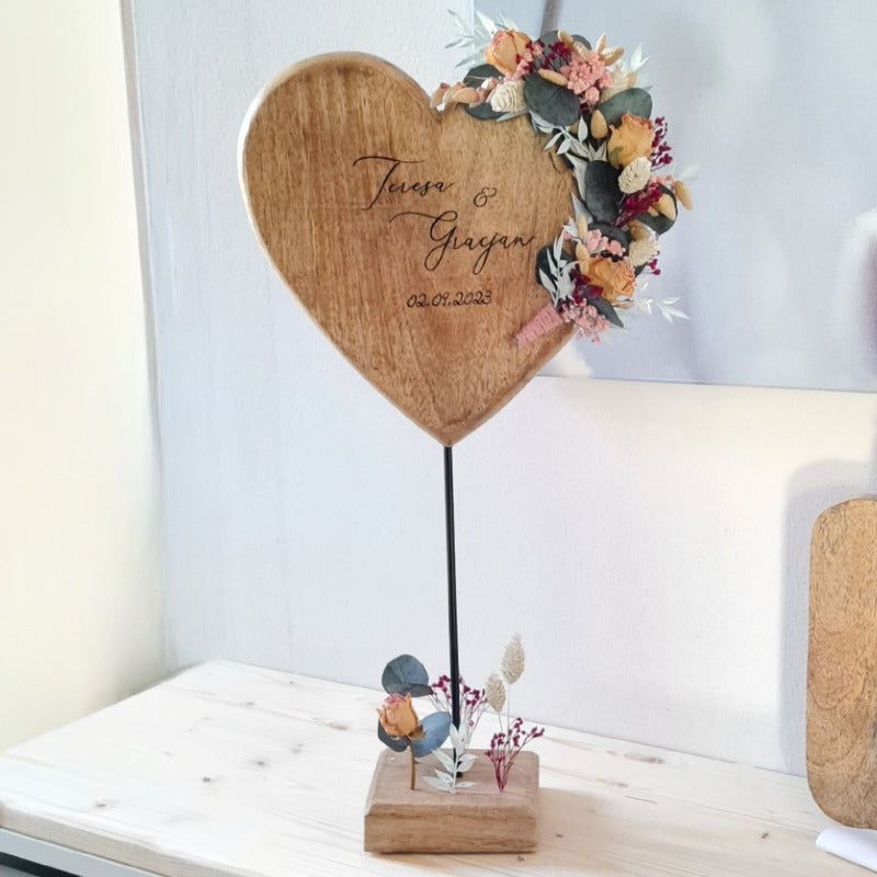 Ein Holzherz aus massivem Holz auf Metallständer, mit Blumenschmuck aus Trockenblumen und mit Wunschtext. Ein einzigartiges Hochzeitsgeschenk für Ehe und Jubiläum.