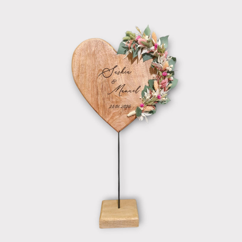 Ein ganz besonderes und ausgefallenes Geschenk zur Hochzeit. Ein Herz aus Holz auf Metallfuß zur Hochzeit. Das Geschenk ist personalisiert und liebevoll mit Blumen geschmückt.. Der Name des Brautpaars und das Datum sind in das Holzherz graviert. Saisonale Trockenblumen dekorieren das Herz.