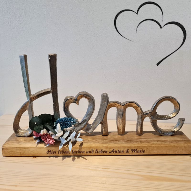 Schriftzug Home aus silberfarbenem Aluminium, das "O" ist als Herz ausgeführt, Lasergravur mit Wunschtext auf der Holzplatte, dezent dekoriert mit Trockenblumen, ein einzigartiges Geschenk zur Hochzeit