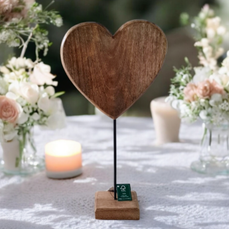 ein Holzherz auf Stönder auf einem Hochzeitstisch. Das Herz wird mit Deinem Wunschtext graviert und ist ein schönes Geschenk für Hochzeit oder silberne und goldene Hochzeit