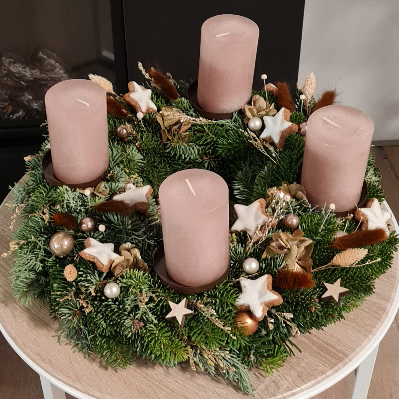 Warme Adventsdekoration mit goldenen Akzenten. Der Kranz mit Zimtsternen und goldenen Trockenblumen ist schlicht elegant und klassisch gebunden mit frischem Grün.