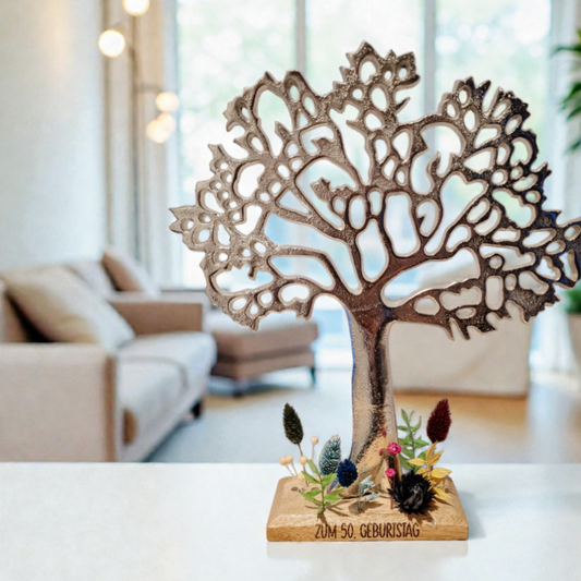 Ein silberer Baum aus Alu mit schön gearbeiteter breiter Krone steht auf einem natürlichem Sockel aus Holz. Die Baumskulptur ist ein schönes Dekoobjekt für Sideboard oder Fensterbrett. Der Holzsockel wird mit Wunschtext graviert, zum Beispiel mit persönlichen Glückwünschen. Es eignet sich als Basis für ein selbstgemachtes Geldgeschenk zum runden Geburtstag.