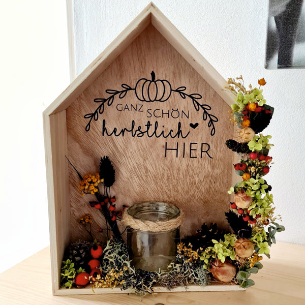 Moderne Herbstdekoration, ein Dekohaus aus Holz mit herbstlichen Trockenblumen und Teelichthalter