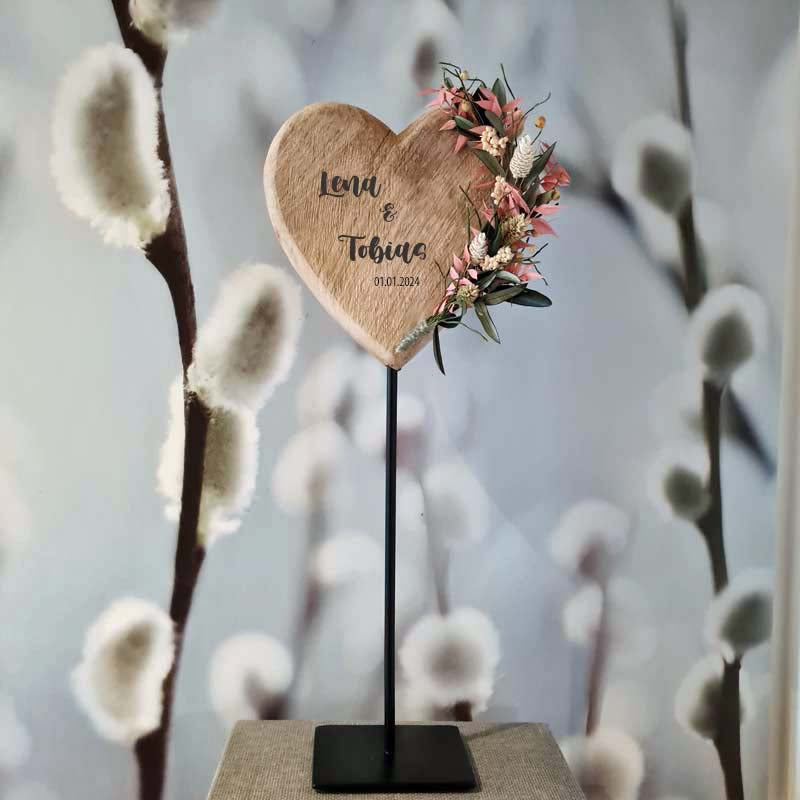 Ein Holzherz aus massivem Holz auf Metallständer, mit Blumenschmuck aus Trockenblumen und  mit Wunschtext. Ein einzigartiges Hochzeitsgeschenk für Ehe und Jubiläum.