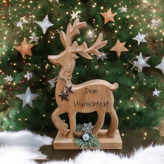 Ein hübsch gearbeitetes Rentier aus Holz wird nach Deinem Wunsch mit Motiv oder Text lasergraviert. Die Figur wird mit weihnachtlichem Grün verziert und trägt ein Band mit zwei silbernen Sternen um den Hals. Eine ganz besondere Geschenkidee für Mama, Oma oder Opa, Jäger und Waldliebhaber.