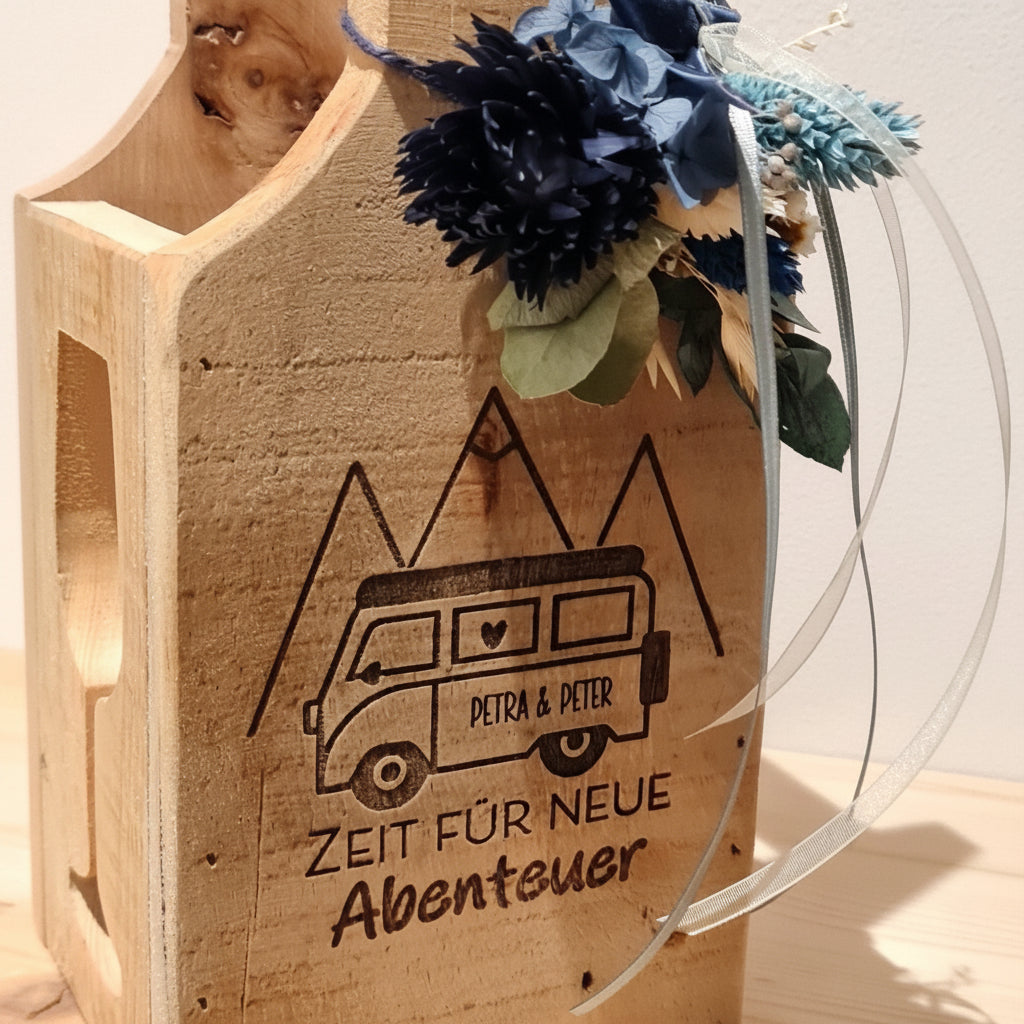Detailansicht einer mit Gravur personalisierten Flaschenbox zum Ruhestand. Mit Blumen dekoriert und mit persönlicher Widmung auf rustikalem Holztragerl.