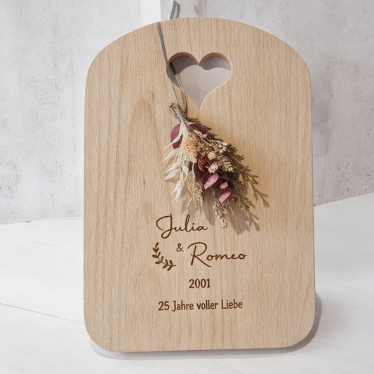 Eichenbrett mit Gravur auf hellem Betonhintergrund, Geschenk mit dezenten Blumendetails, elegant zum Jahrestag und Hochzeitstag, edel