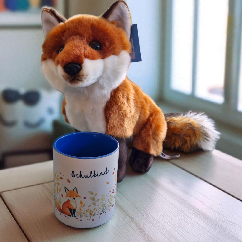 Kuscheliger Plüschfuchs mit passender Fuchs-Tasse auf einem Tisch, umgeben von herbstlicher Deko – perfektes Geschenkset für den ersten Schultag zur Einschulung.