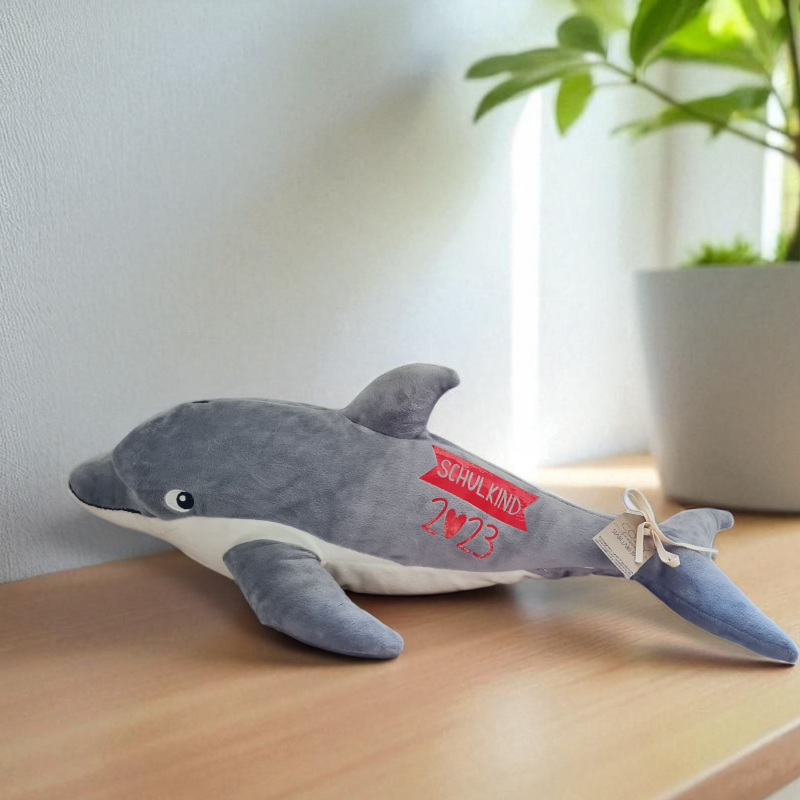 Ein bezaubernder Delfin aus weichem Plüsch, für Kinder zum ersten Schultag personalisiert. Er trägt einen Schriftzug "endlich Schulkind" und ist das perfekte Geschenk zur Einschulung. Ein süßer Begleiter zur Schultüte und in der Zuckertüte zum Schulanfang.