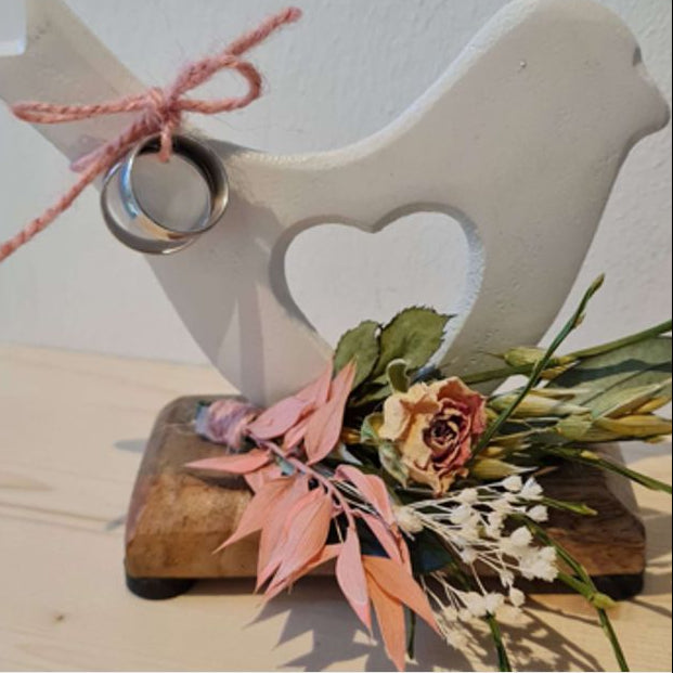 Weiße Aluminiumtaube mit Blumenschmuck in Wunschfarbe auf Holzplatte, Platte ist mit Namen und Datum lasergravierbar.