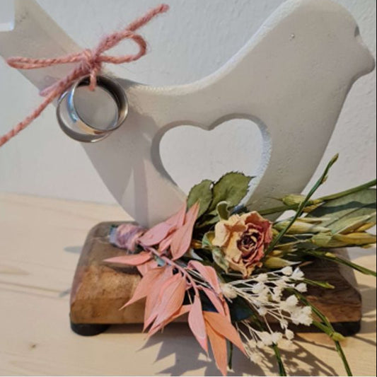 Weiße Aluminiumtaube mit Blumenschmuck in Wunschfarbe auf Holzplatte, Platte ist mit Namen und Datum lasergravierbar.