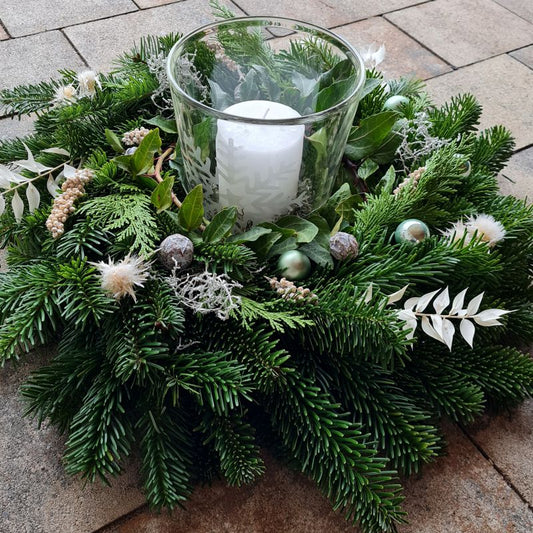 Winterkranz gebunden aus frischem Tannengrün mit Trockenblumen, Windlicht und Kerze